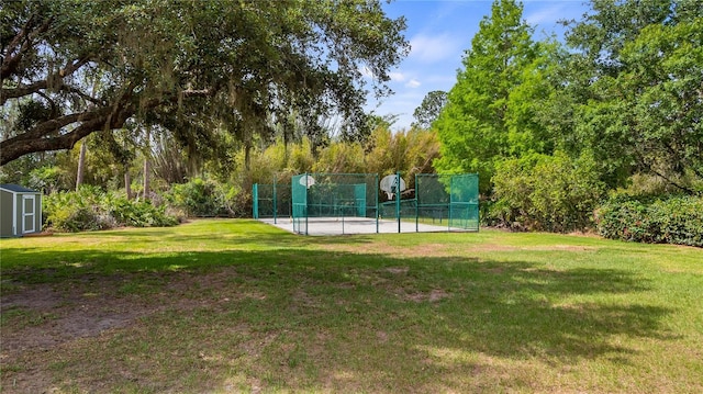 view of sport court with a lawn, fence, playground community, and a storage unit