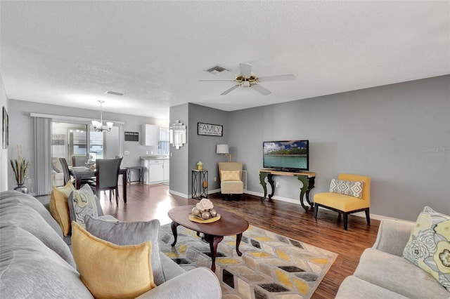 living area with baseboards, visible vents, wood finished floors, and ceiling fan with notable chandelier