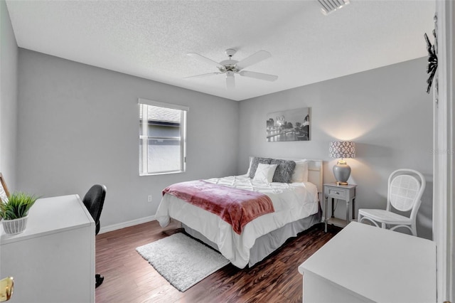 bedroom featuring a textured ceiling, baseboards, ceiling fan, visible vents, and dark wood-style floors