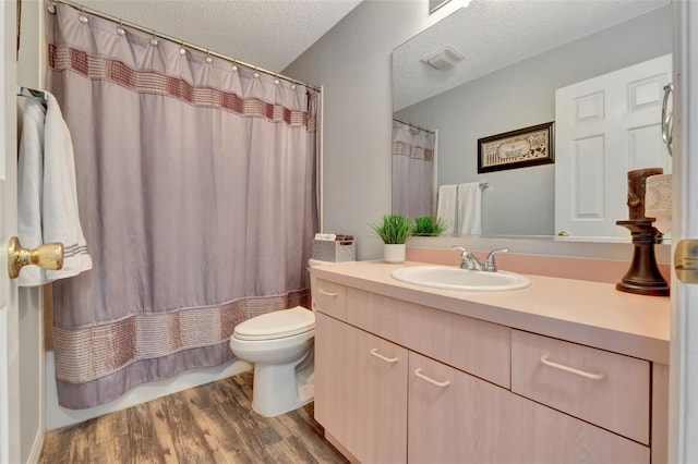 bathroom with toilet, vanity, a textured ceiling, and wood finished floors