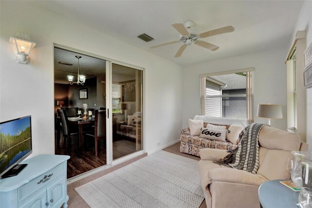 living room featuring visible vents, carpet floors, and ceiling fan with notable chandelier