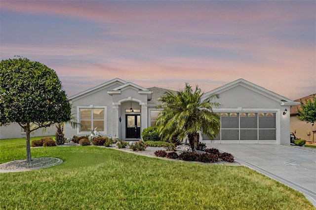 ranch-style house featuring stucco siding, an attached garage, driveway, and a front lawn