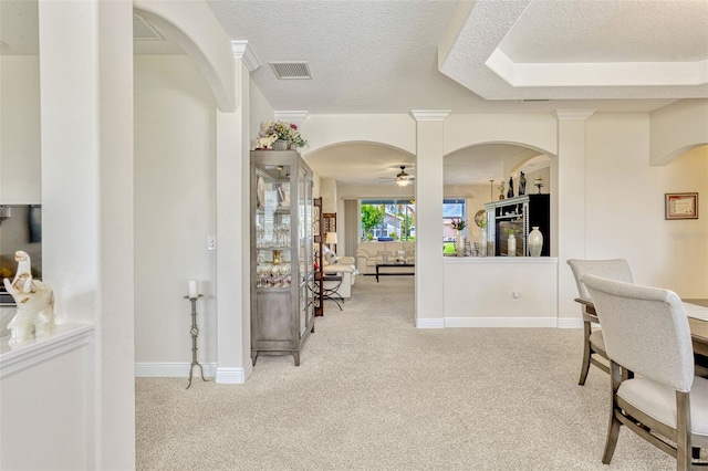 interior space with carpet flooring, arched walkways, a textured ceiling, and visible vents
