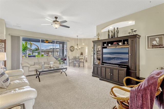 carpeted living room featuring ceiling fan with notable chandelier