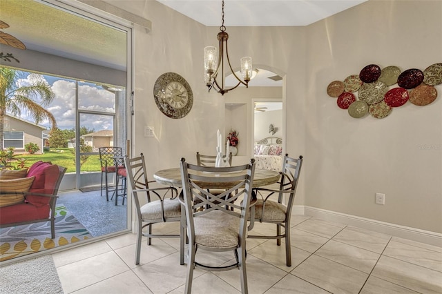 dining room featuring light tile patterned floors, arched walkways, baseboards, and a notable chandelier