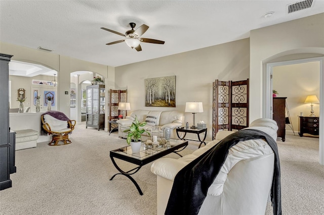 living room with arched walkways, light colored carpet, visible vents, and ceiling fan