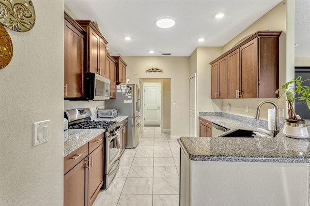 kitchen featuring a sink, stone countertops, marble finish floor, stainless steel appliances, and a peninsula
