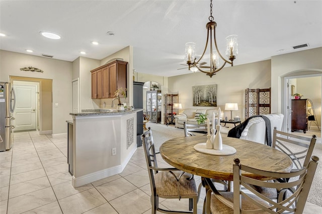 dining room with light tile patterned floors, arched walkways, a chandelier, and visible vents