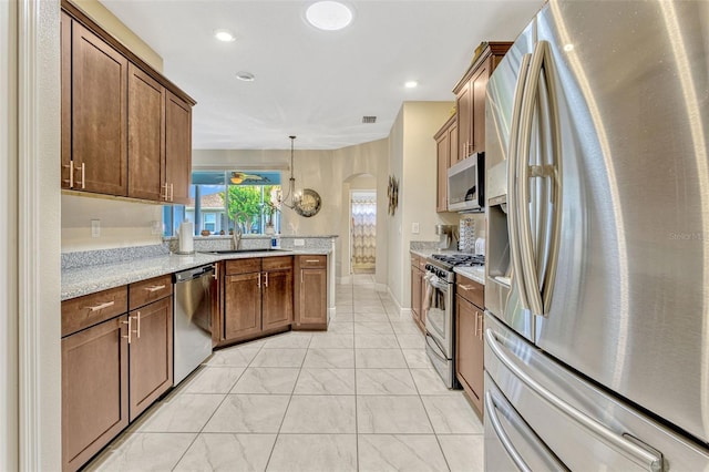kitchen featuring appliances with stainless steel finishes, light stone counters, a sink, arched walkways, and marble finish floor