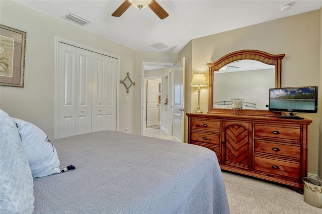 bedroom featuring a ceiling fan, visible vents, light carpet, and a closet
