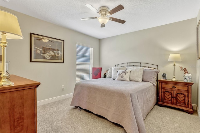 bedroom with a textured ceiling, baseboards, light colored carpet, and a ceiling fan