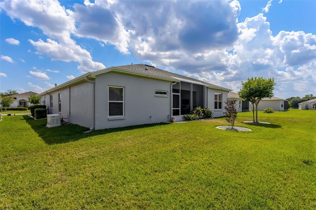 rear view of house featuring a yard, stucco siding, and central air condition unit