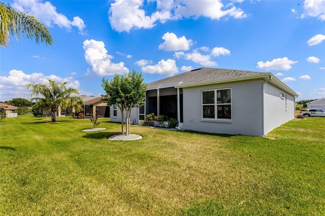 rear view of house with stucco siding and a yard