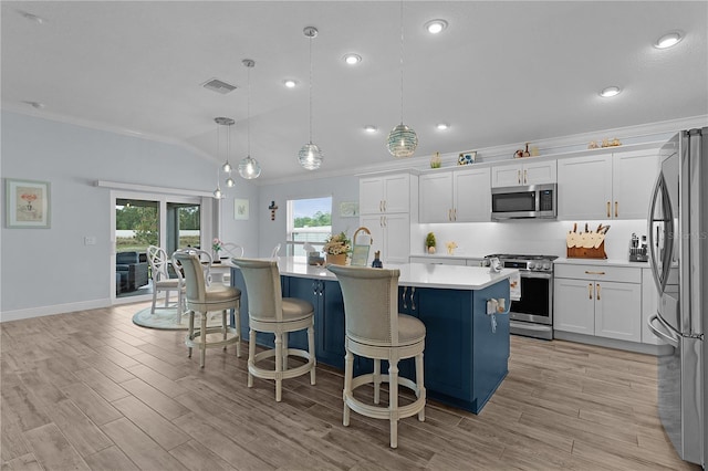 2129 Landrea Loop, The Villages, FL 32163 - kitchen featuring ornamental molding, a kitchen island with sink, light countertops, appliances with stainless steel finishes, and vaulted ceiling