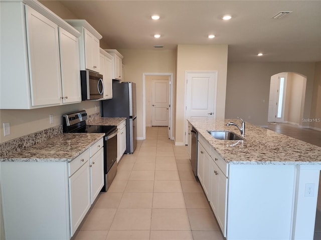 kitchen with a sink, appliances with stainless steel finishes, white cabinets, and a kitchen island with sink