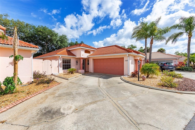 mediterranean / spanish home with an attached garage, stucco siding, a tile roof, and concrete driveway