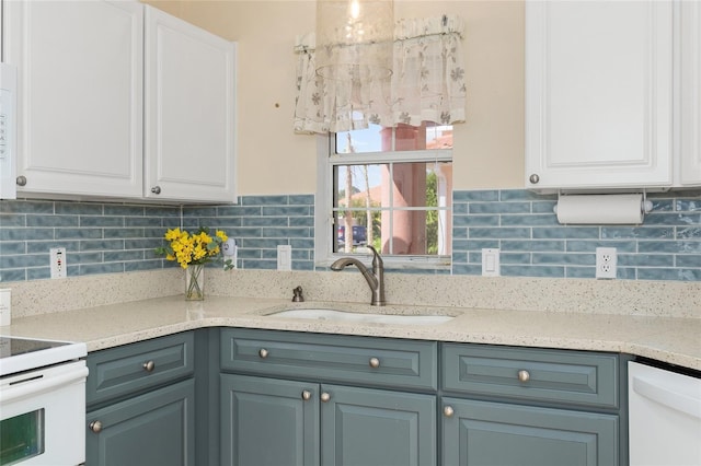kitchen featuring a sink, white cabinets, backsplash, and white appliances