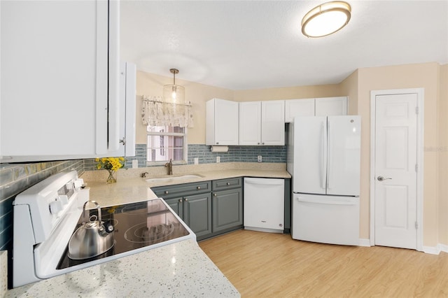 kitchen featuring light wood-style floors, a sink, white appliances, and tasteful backsplash