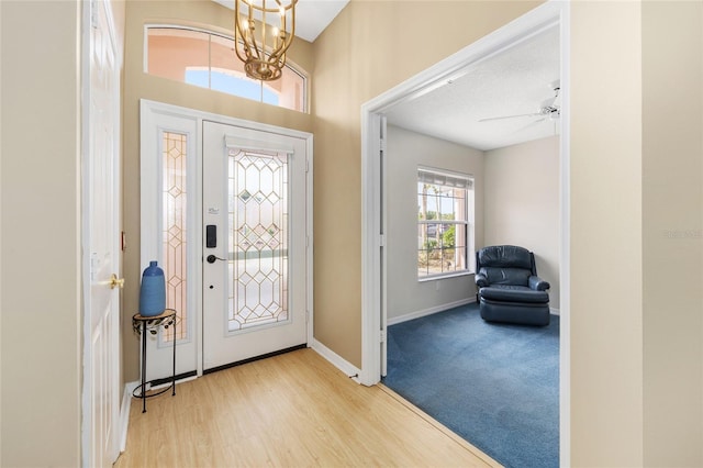 entrance foyer with baseboards, wood finished floors, and ceiling fan with notable chandelier