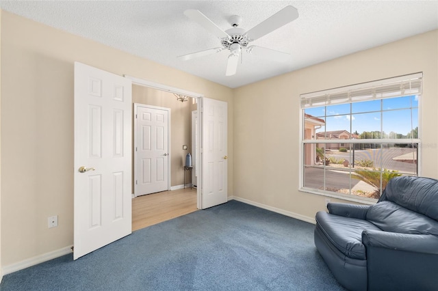 sitting room with carpet floors, ceiling fan, baseboards, and a textured ceiling