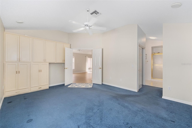 unfurnished bedroom featuring dark carpet, baseboards, lofted ceiling, and visible vents