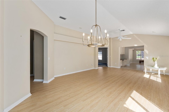 unfurnished dining area featuring light wood finished floors, visible vents, arched walkways, a chandelier, and vaulted ceiling