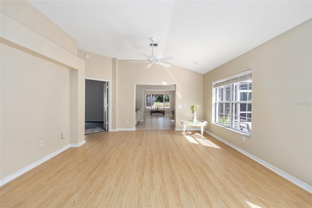 interior space with visible vents, lofted ceiling, light wood-style floors, baseboards, and ceiling fan