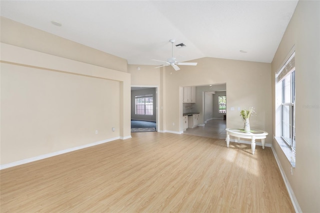 living area with visible vents, baseboards, ceiling fan, light wood-type flooring, and vaulted ceiling