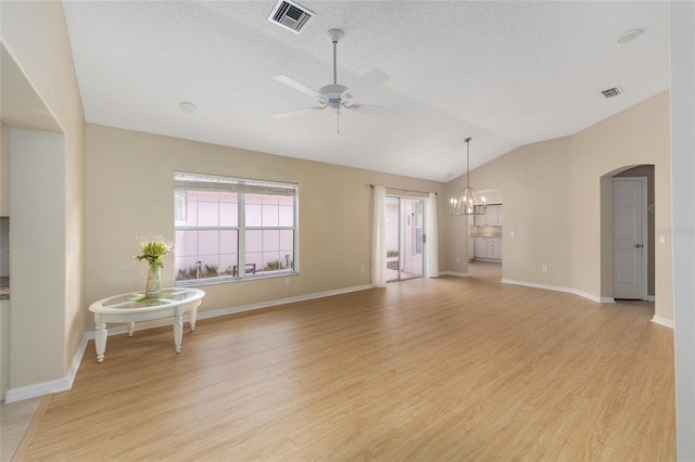 interior space featuring visible vents, light wood-style flooring, ceiling fan with notable chandelier, and vaulted ceiling