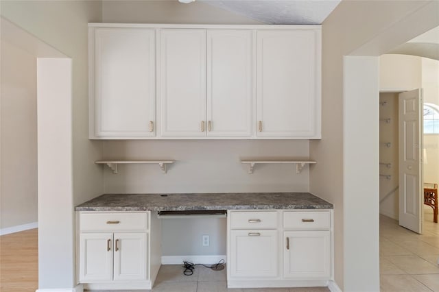 unfurnished office with light tile patterned floors, baseboards, and built in desk