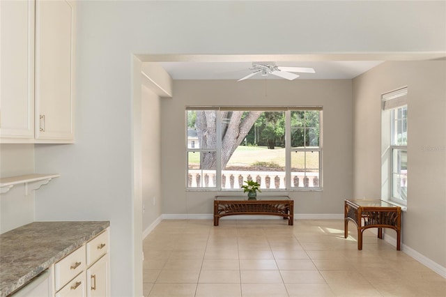 interior space featuring light tile patterned floors, ceiling fan, and baseboards