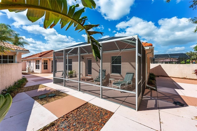 back of house with a lanai, a patio area, stucco siding, and fence