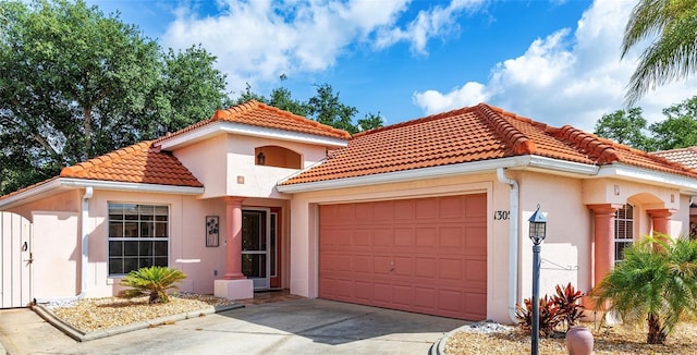 mediterranean / spanish house featuring a tiled roof, an attached garage, and stucco siding