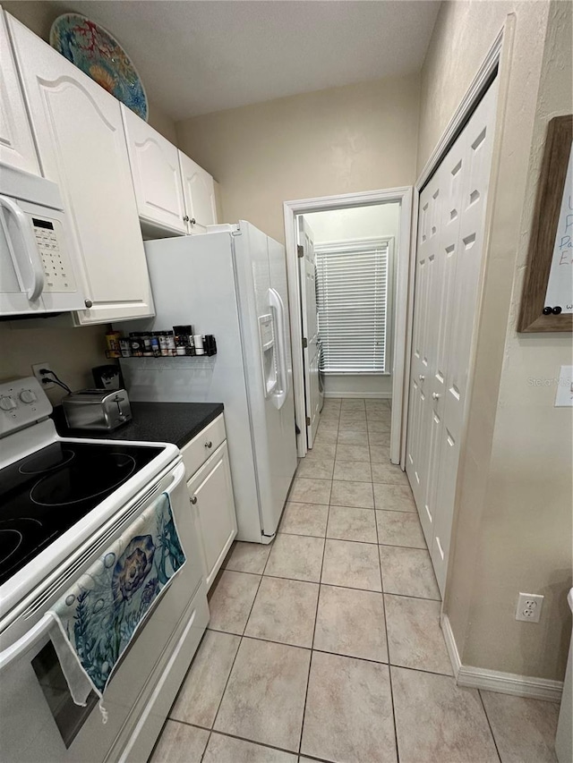54 SE 910th Ave Unit 210/3, Suwannee, FL 32692 - kitchen featuring white appliances, white cabinets, light tile patterned floors, and dark countertops