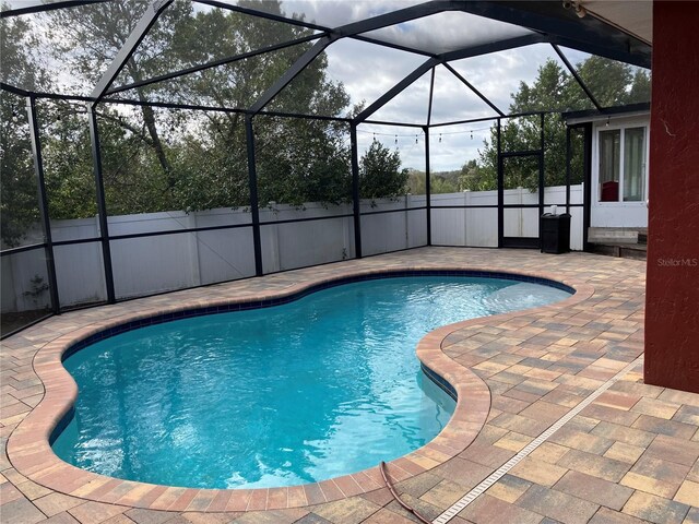 view of pool featuring fence, a fenced in pool, a lanai, and a patio area