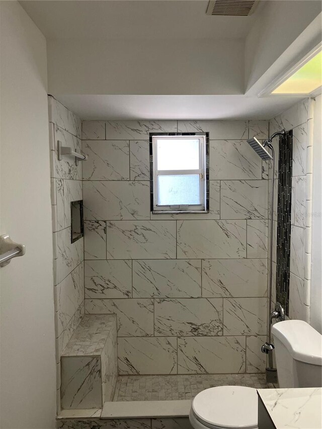 bathroom with vanity, a shower stall, toilet, and visible vents