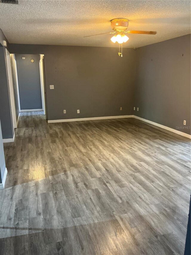 unfurnished room featuring a textured ceiling, ceiling fan, baseboards, and wood finished floors
