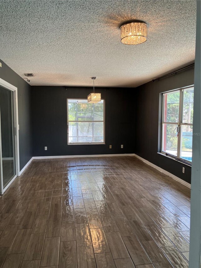 spare room with a wealth of natural light, a textured ceiling, and visible vents