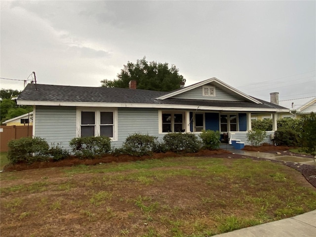 view of front of property featuring a porch, a chimney, a front yard, and fence