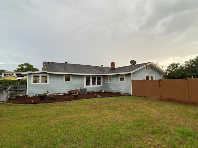 rear view of property featuring central AC, fence, and a yard