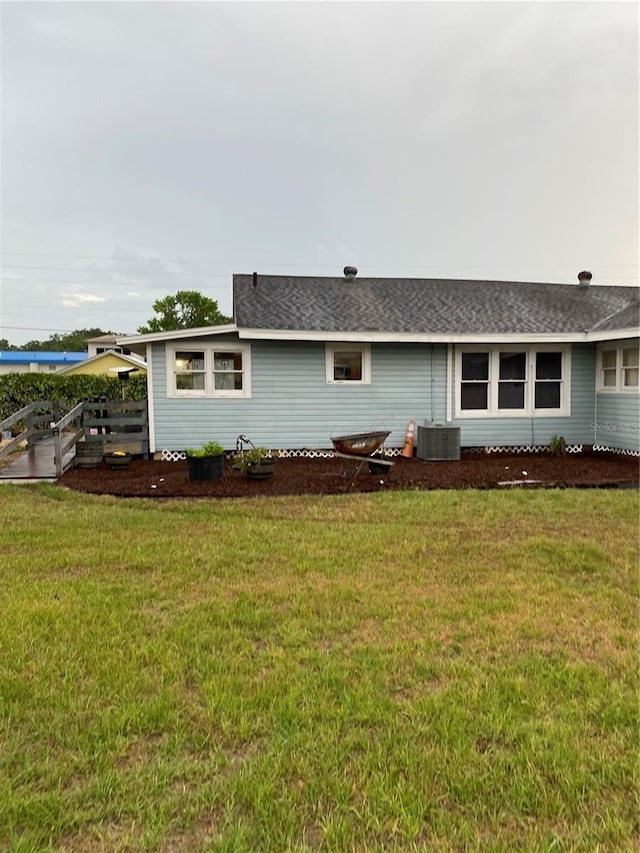 rear view of house featuring a lawn, fence, and cooling unit