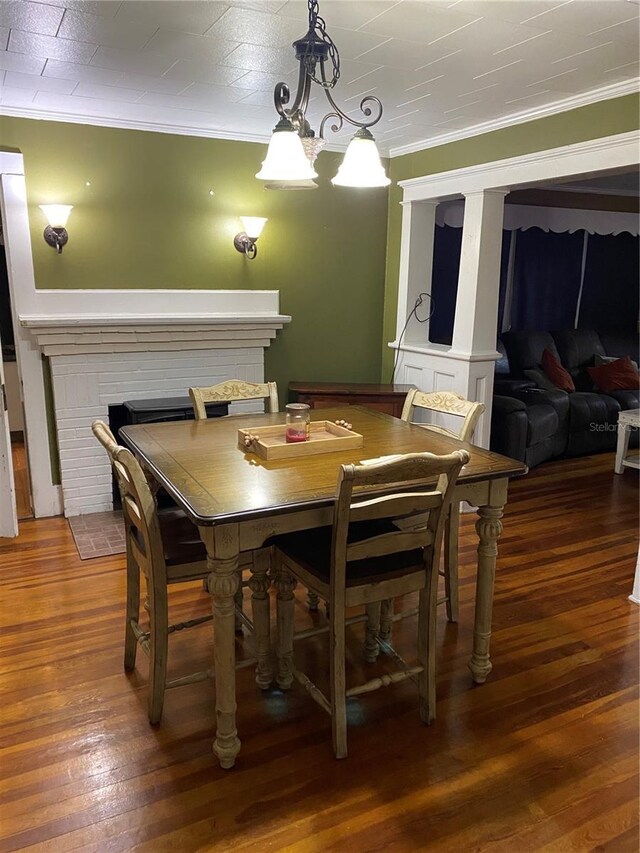 dining space featuring ornamental molding, a fireplace, and wood-type flooring
