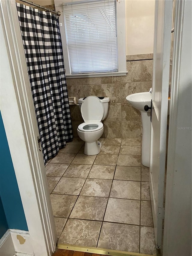 full bath with tile patterned flooring, toilet, tile walls, a shower with curtain, and a sink