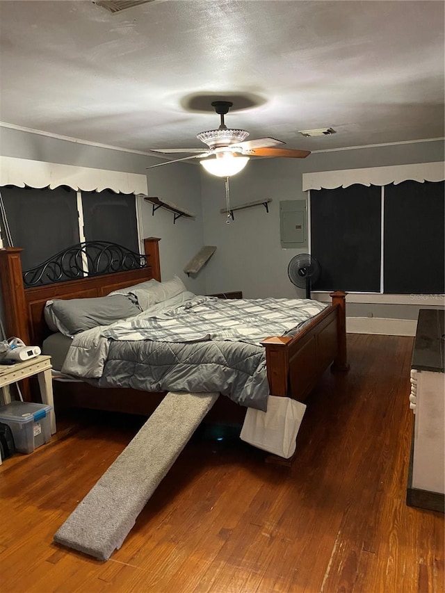 bedroom featuring electric panel, a ceiling fan, wood finished floors, and visible vents