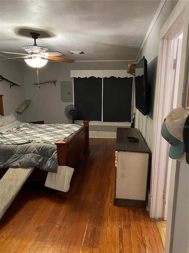 bedroom with crown molding, electric panel, wood finished floors, and visible vents