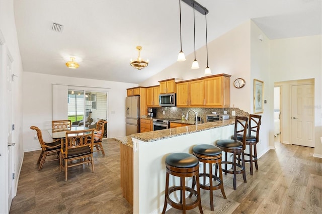 kitchen featuring visible vents, appliances with stainless steel finishes, light stone countertops, a peninsula, and lofted ceiling