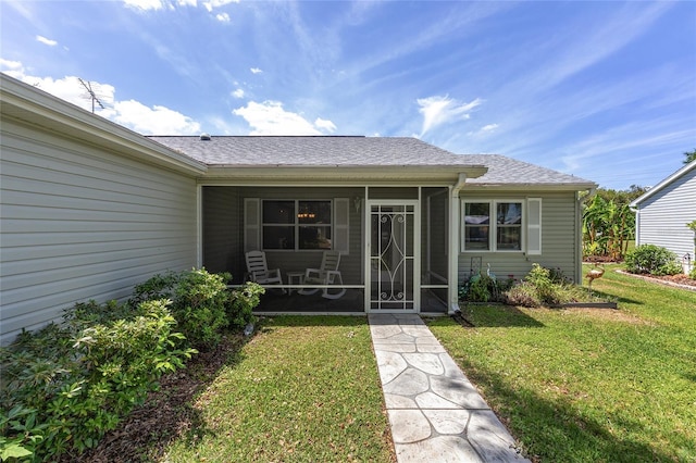 entrance to property with a shingled roof and a yard