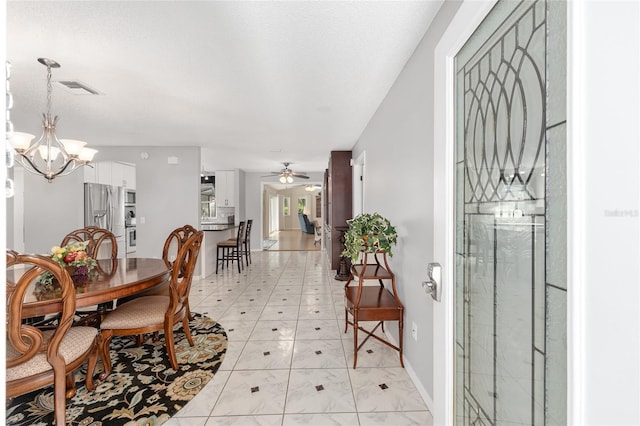 dining area with baseboards, ceiling fan with notable chandelier, and visible vents