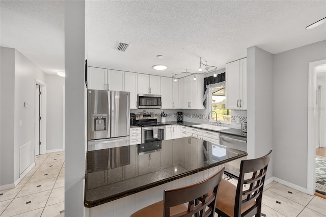 kitchen with white cabinets, light tile patterned flooring, a sink, stainless steel appliances, and visible vents