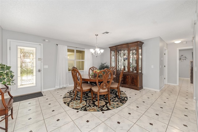 dining area featuring visible vents, baseboards, a textured ceiling, light tile patterned floors, and a notable chandelier